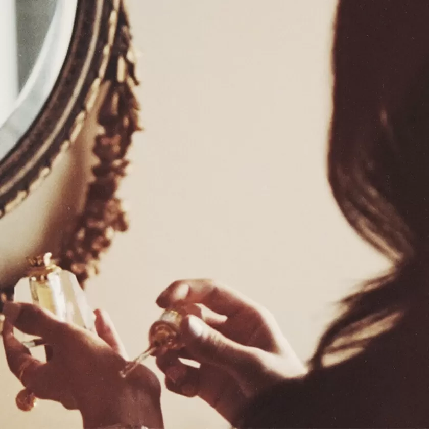 Zohoor. Image with a lady applying fragrance oil on her hand